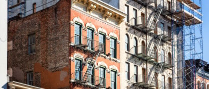 Traditional apartment buildings in New York City, circa 2019, building with scaffolding outside of it.